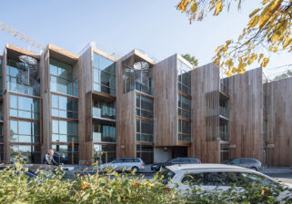 Dettaglio del prospetto su strada con il rivestimento delle pareti in legno di cedro, le grandi superfici vetrate e i giardini pensili in sommità