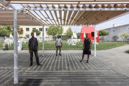 Alcuni membri del gruppo di detenuti che ha condotto il lavoro di autocostruzione, sotto la pergola risistemata con il sistema frangisole in legno di cedro, al centro del giardino degli incontri. Sullo sfondo la "Casetta rossa"